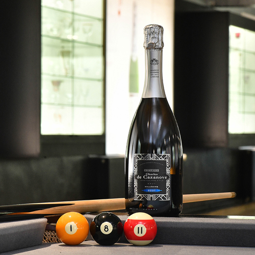 Bouteille de champagne Charles de Cazanove Millésime 2016 sur un billard avec 3 boules de billard alignées : la numéro 1, la 8 et la 8 pour former 1811 date de création de la maison / Bottle of Charles de Cazanove Millésime 2016 champagne on a billiard table with 3 billiard balls lined up: the number 1, the 8 and the 8 to form 1811, the date of creation of the house.
