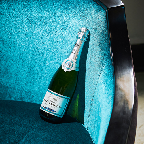 Bouteille de champagne Charles de Cazanove brut nature posée sur l’assise d’un fauteuil / Bottle of Charles de Cazanove brut champagne on the seat of an armchair