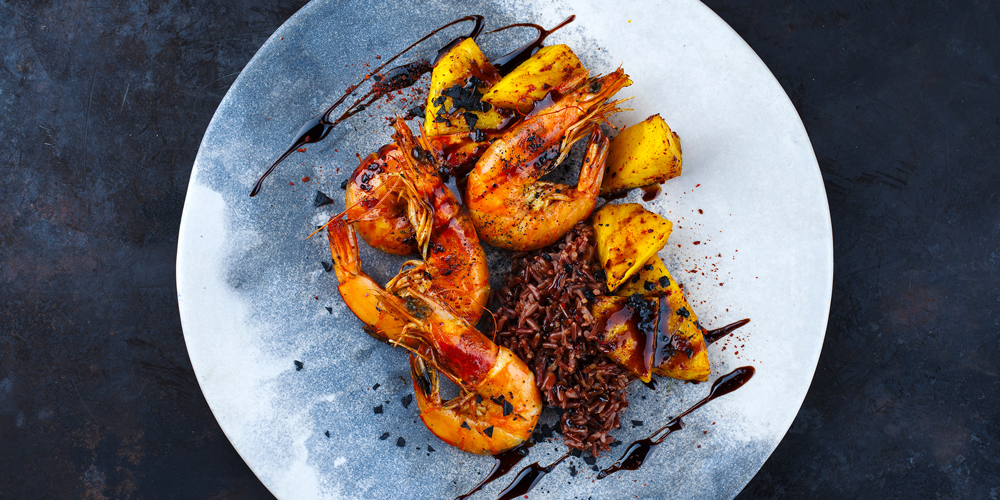 Quatre gambas et riz safrané dans une assiette ronde, vinaigre balsamique en filet et mangue / Four prawns and saffron rice on a round plate, drizzled balsamic vinegar and mango