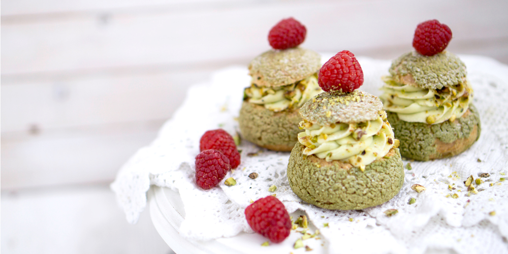 trois choux farcis à la crème de pistache dans une assiette / three choux pastries stuffed with pistachio cream on a plate